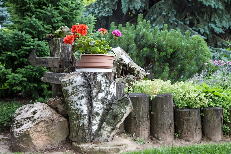 Blumige Gartenecke mit Holzscheiten