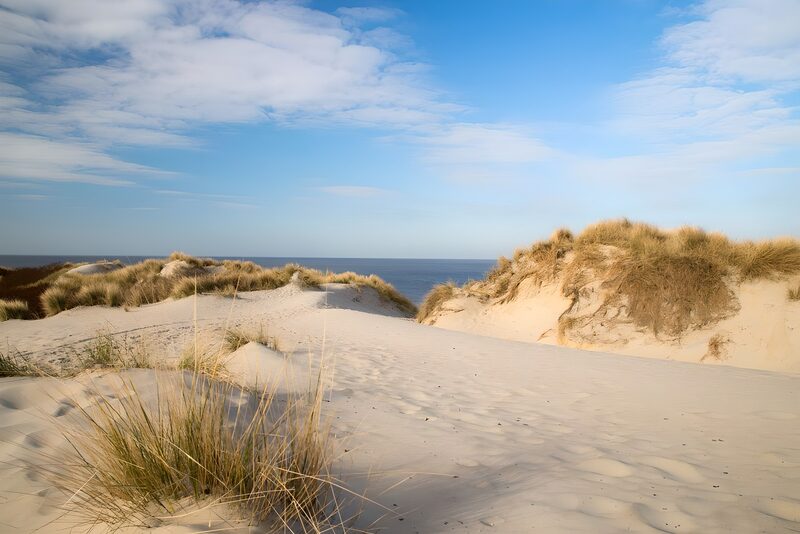 Sanddünen am Meer unter blauem Himmel
