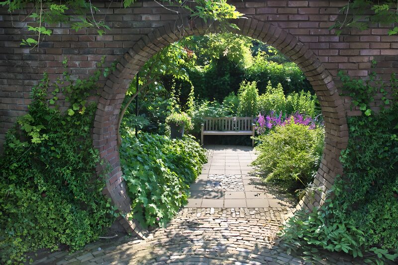 Gemütlicher Gartenweg durch einen Torbogen